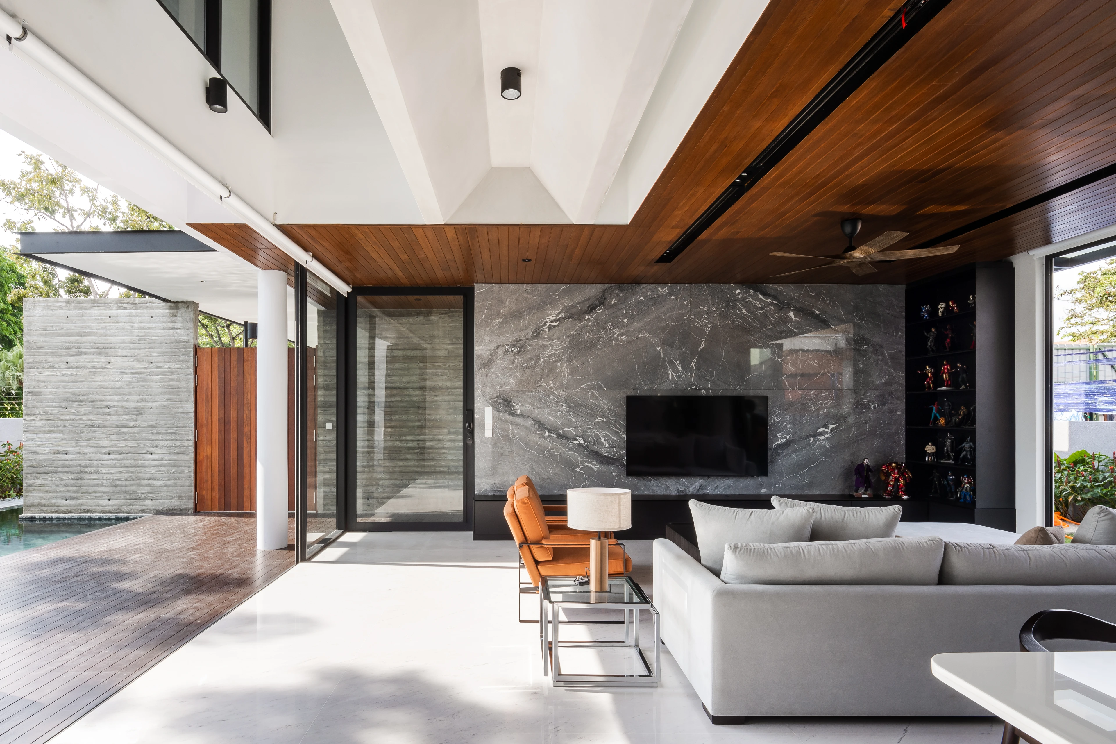 Living room beneath a timber ceiling, opening towards the pool